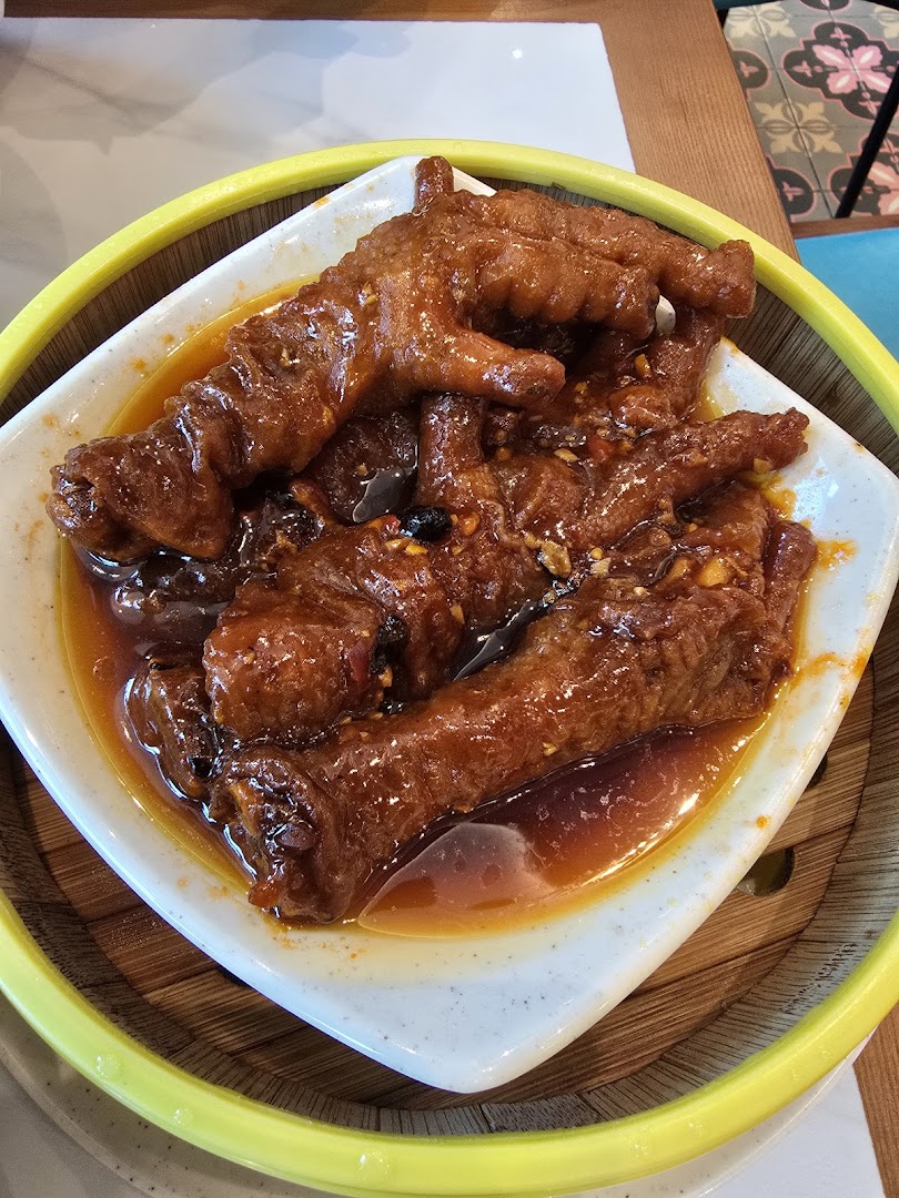 Close-up of braised chicken feet in a white dish within a steamer.