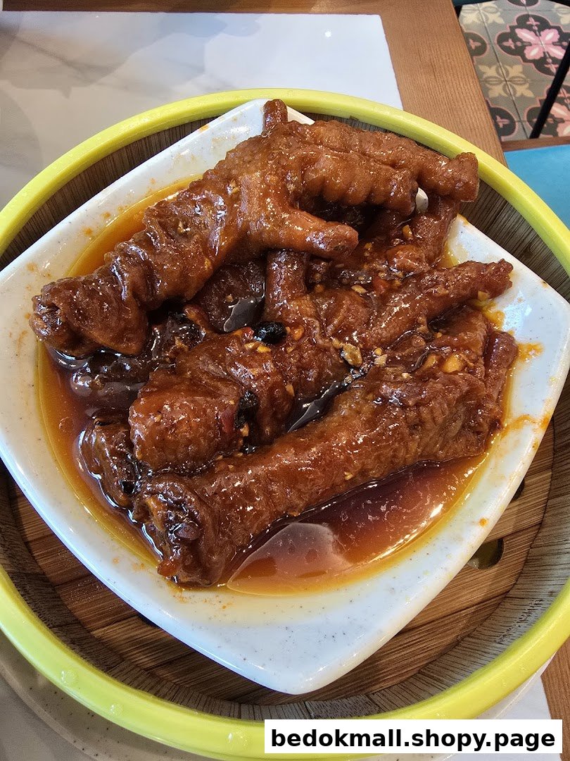 Close-up of braised chicken feet in a white dish within a steamer.