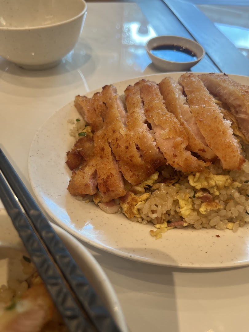 Plate of fried rice with sliced fried meat, chopsticks, and a sauce bowl.