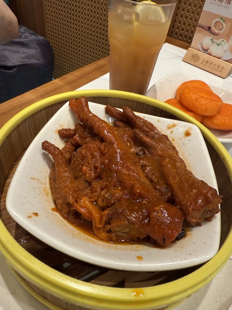 Plate of chicken feet and orange buns with a drink on a table.