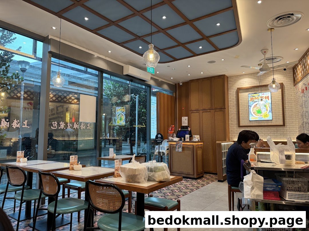 Interior view of a restaurant with tables, chairs, customers, and large windows.
