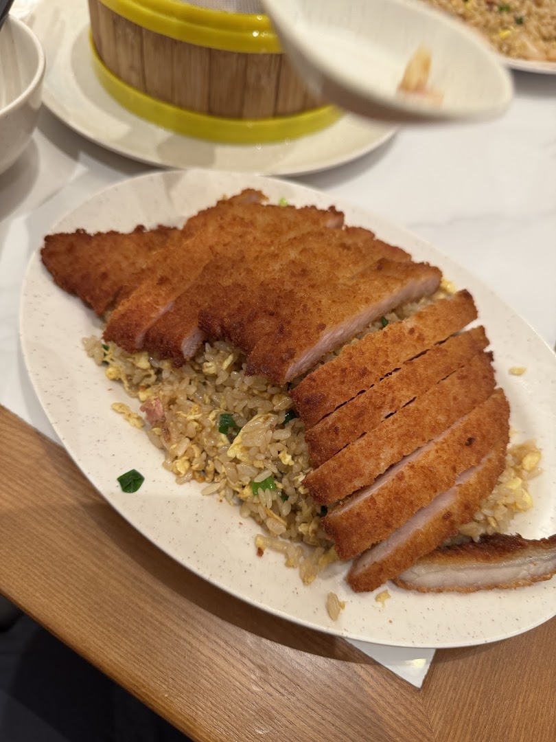 A plate of fried rice topped with sliced breaded pork cutlet.