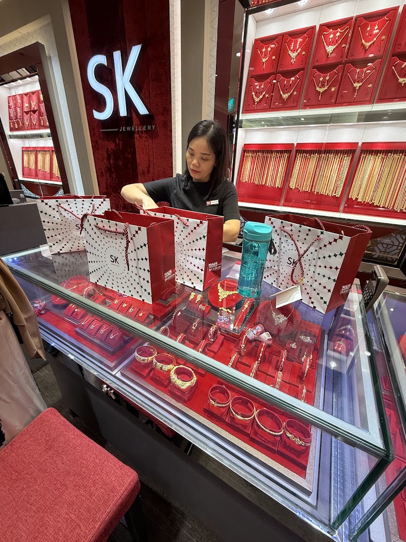 Staff member at counter with jewellery displays and shopping bags in a shop.