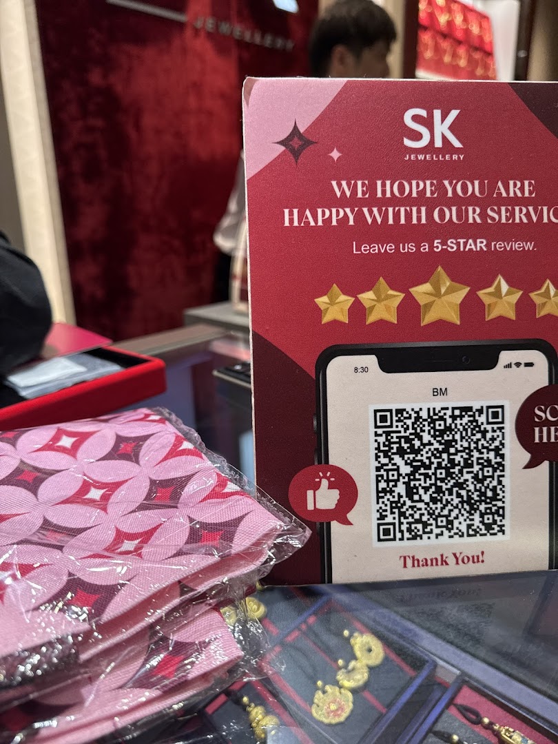 Close-up of a review sign with QR code and packaged items in a jewelry store.