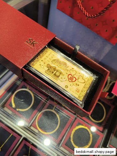 Gold bar in a red box and gold bangles in a display case.