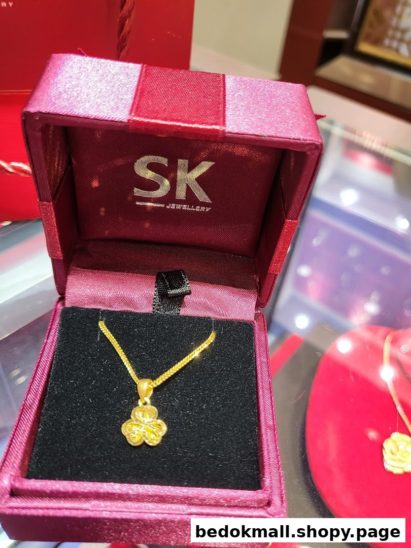 Gold necklace in an open jewelry box with SK Jewellery logo.