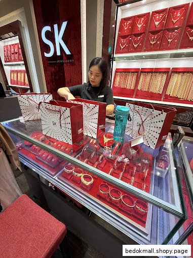 Staff member at a jewellery counter with display cases and shopping bags.