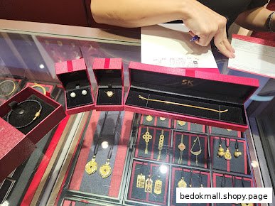 Jewelry items in display cases and red boxes, with a hand signing a document.