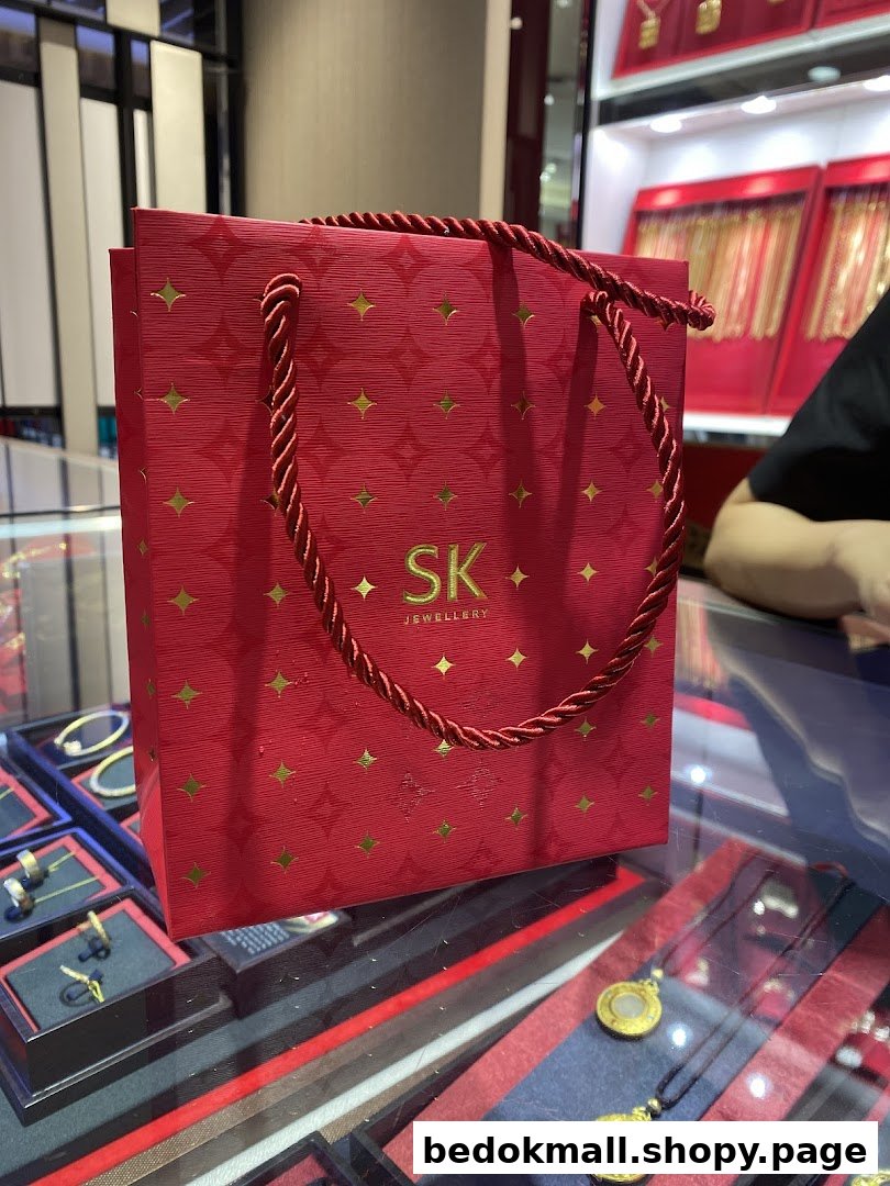 Red SK Jewellery shopping bag on a display counter with jewelry.