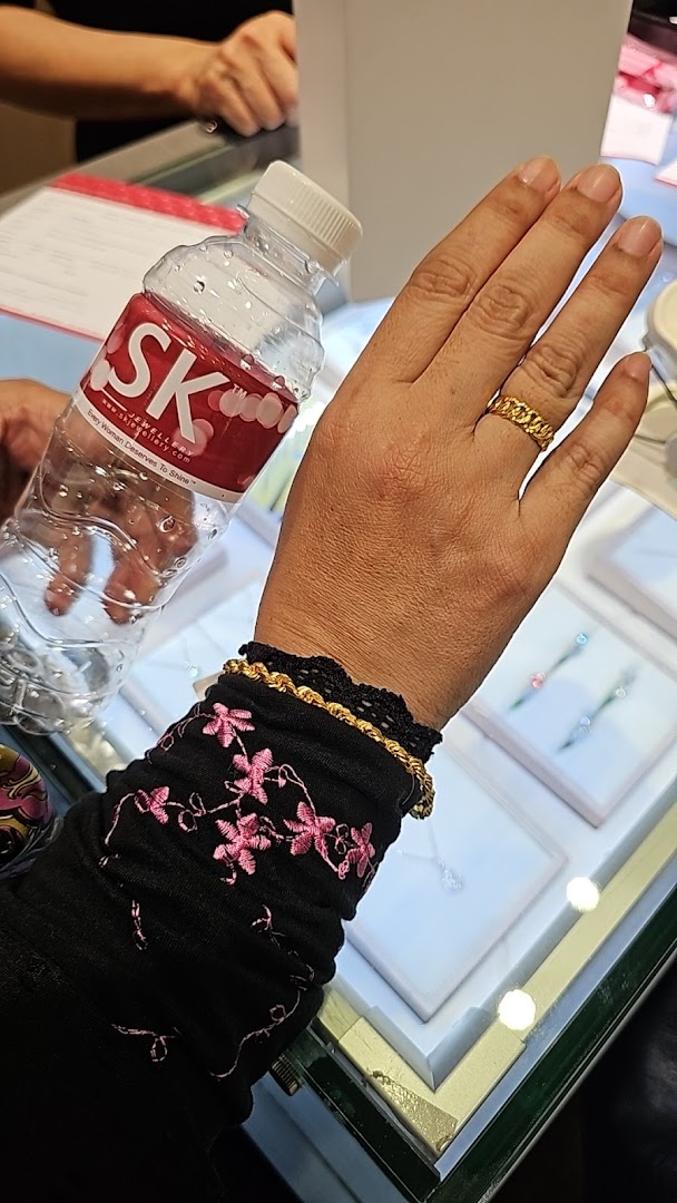 Customer's hand with jewelry and branded water bottle inside a shop.