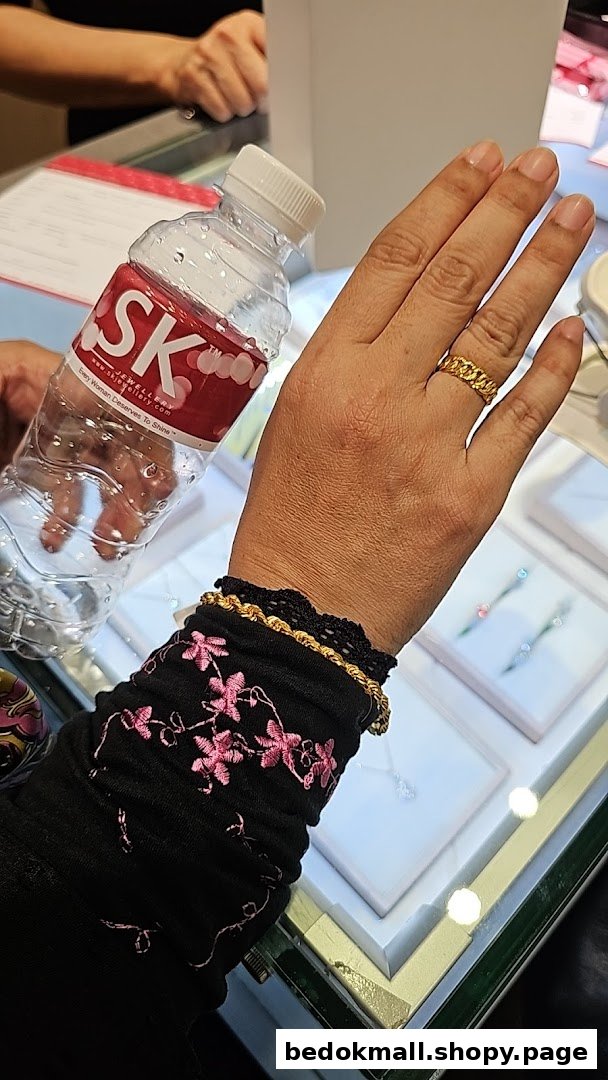 Customer's hand with jewelry and branded water bottle inside a shop.