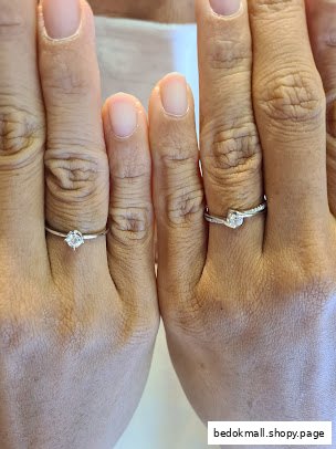 Two hands displaying engagement rings on fingers.