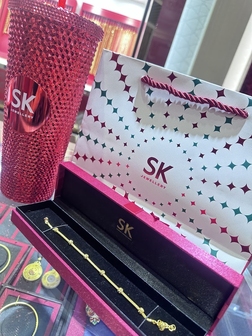 Gold bracelet in box with SK Jewellery bag and tumbler.