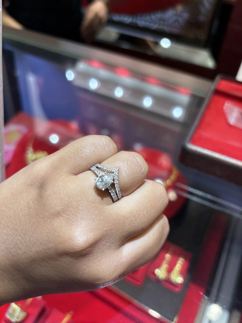 Hand wearing a diamond ring in a jewelry store display case.