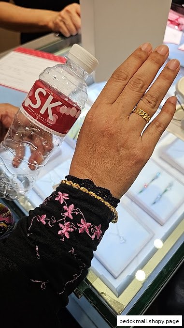 Customer's hand with jewelry and SK water bottle inside a jewelry shop.