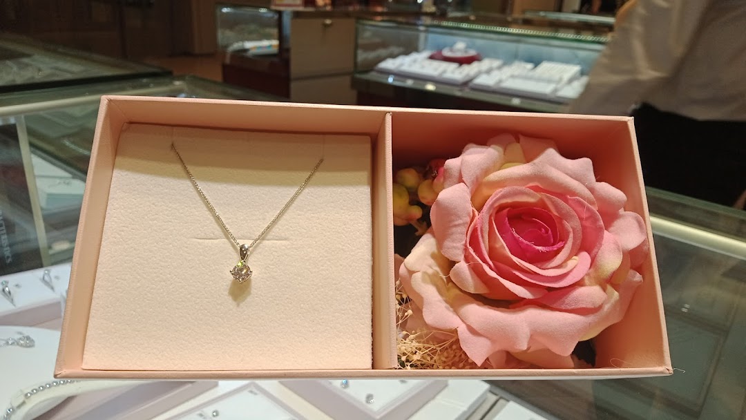 Pink box with a necklace and a rose, displayed in a jewelry store.