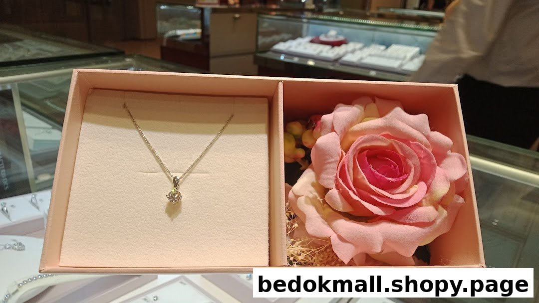 Pink box with a necklace and a rose, displayed in a jewelry store.