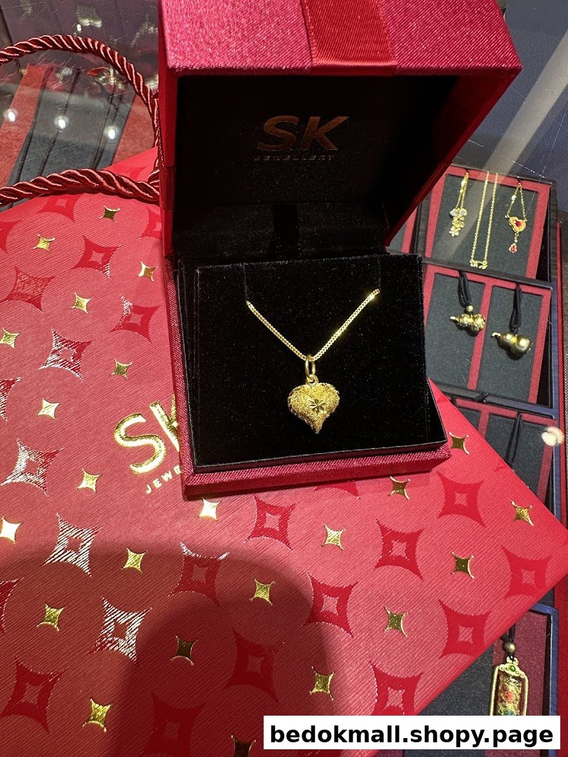 Gold necklace in a red box on a matching shopping bag with other jewelry visible.