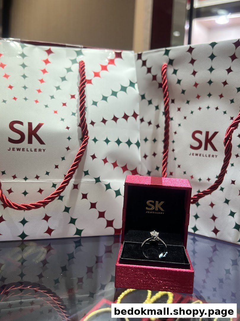 A diamond ring in a red box with SK Jewellery shopping bags on a display.