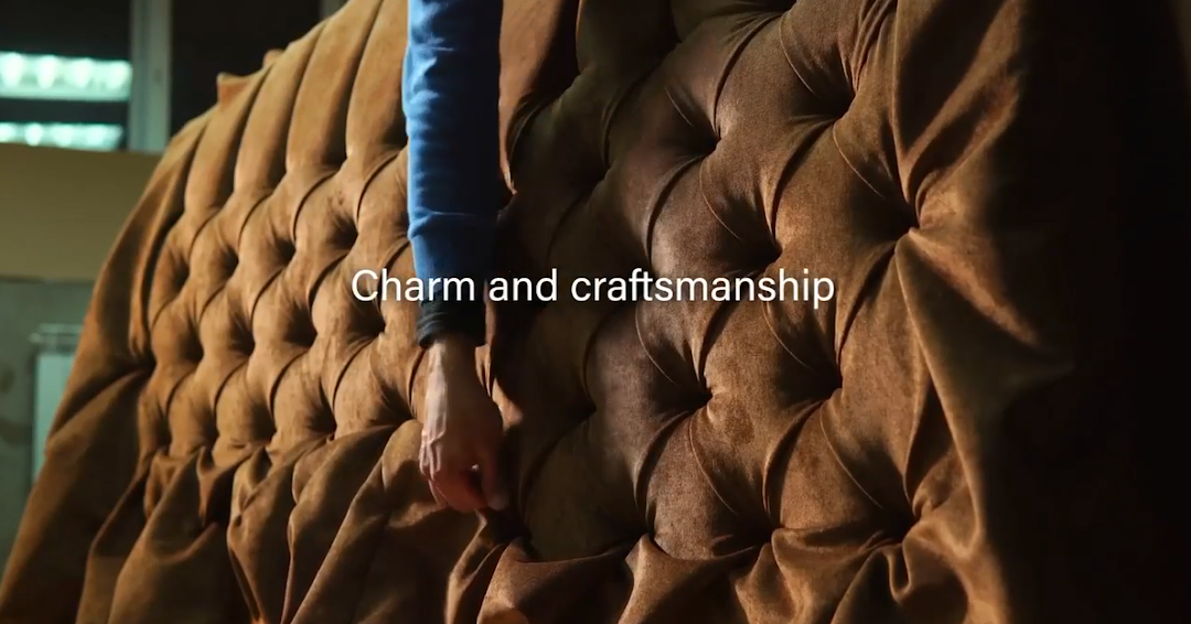 Close-up of tufted brown upholstery with a person's arm touching it.