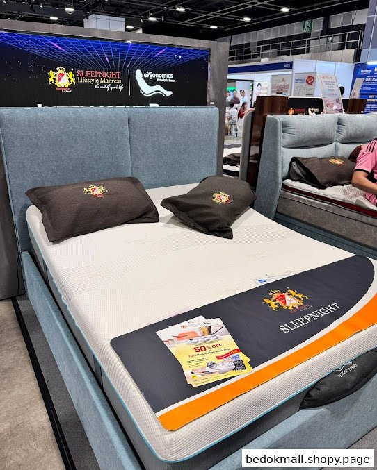 A mattress display with pillows and promotional materials in a showroom setting.