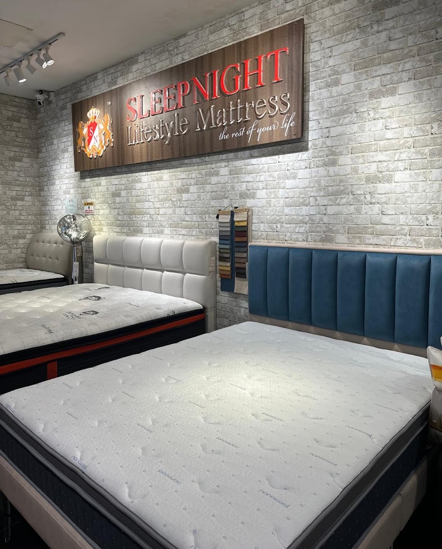 Interior view of a mattress showroom with several beds and a brand sign.