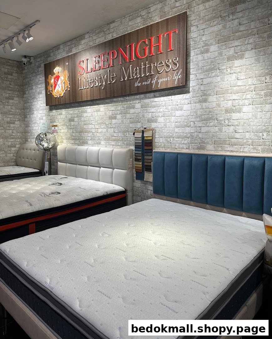 Interior view of a mattress showroom with several beds and a brand sign.