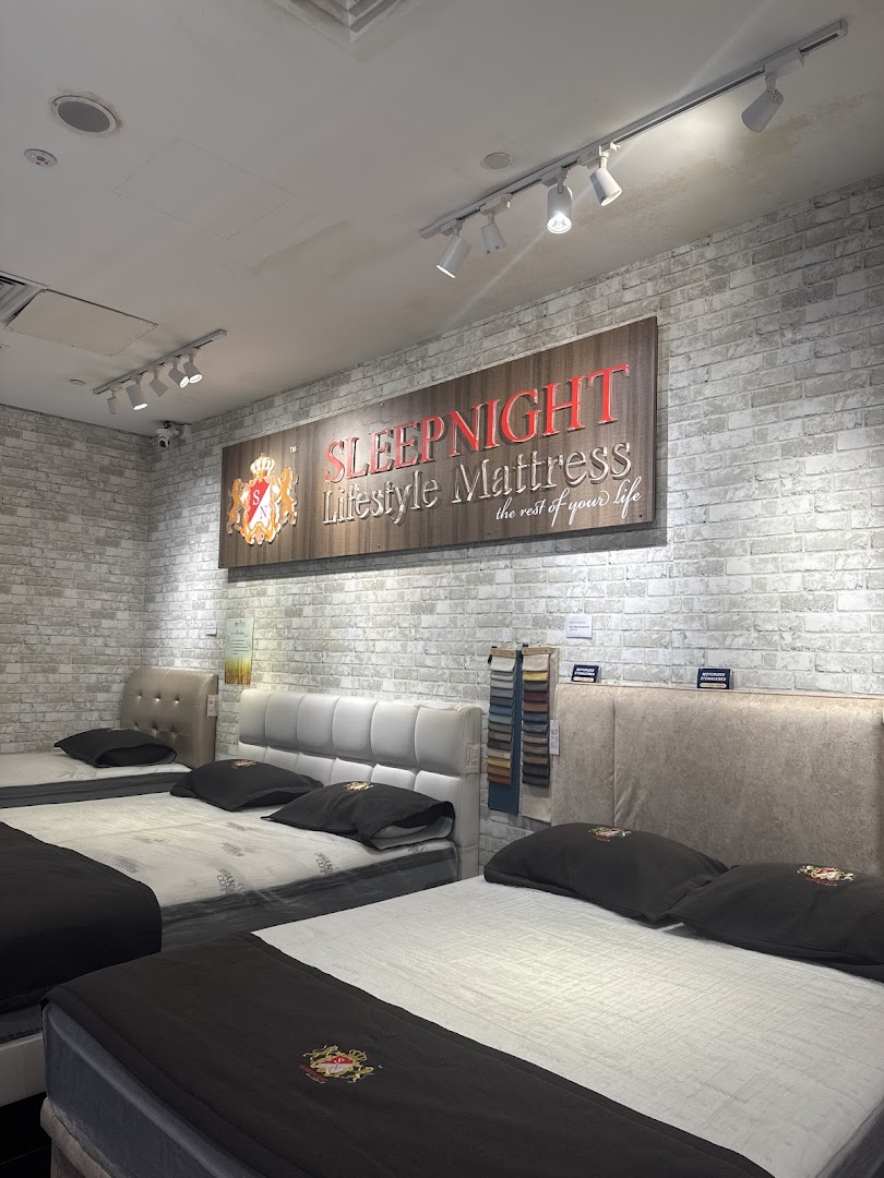 Interior view of a mattress showroom with multiple beds and a brand sign.