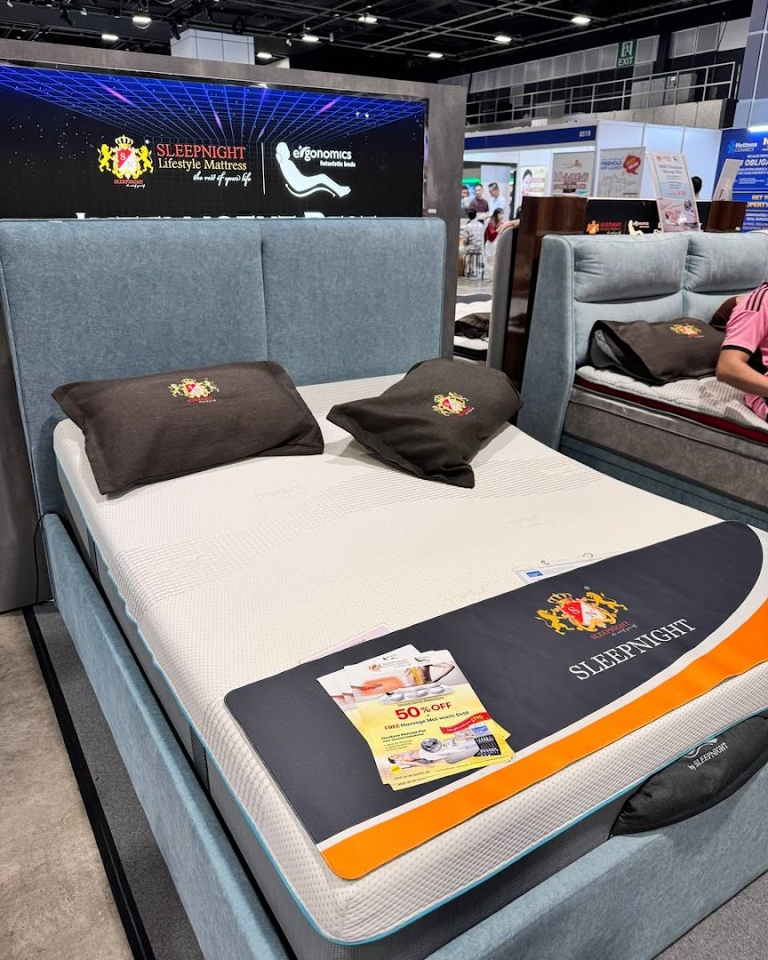 A bed display featuring a mattress, pillows, and a large promotional screen.