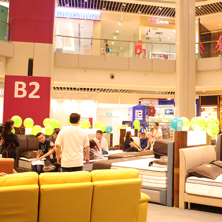 People testing mattresses and furniture in a mall setting with balloons.