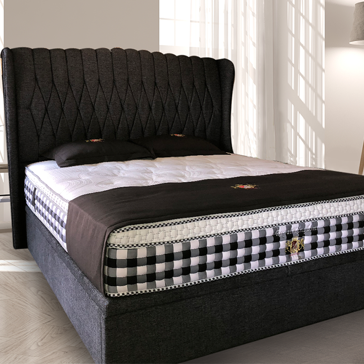 A bed with a dark headboard and a black and white checkered mattress.
