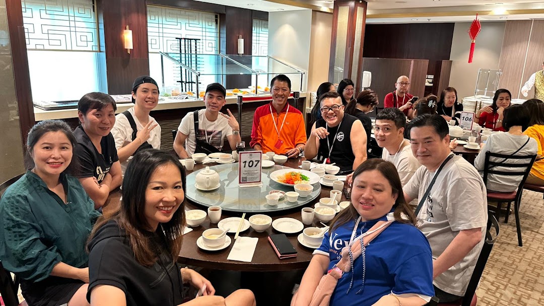 Group of people smiling and dining at a large round table in a restaurant.