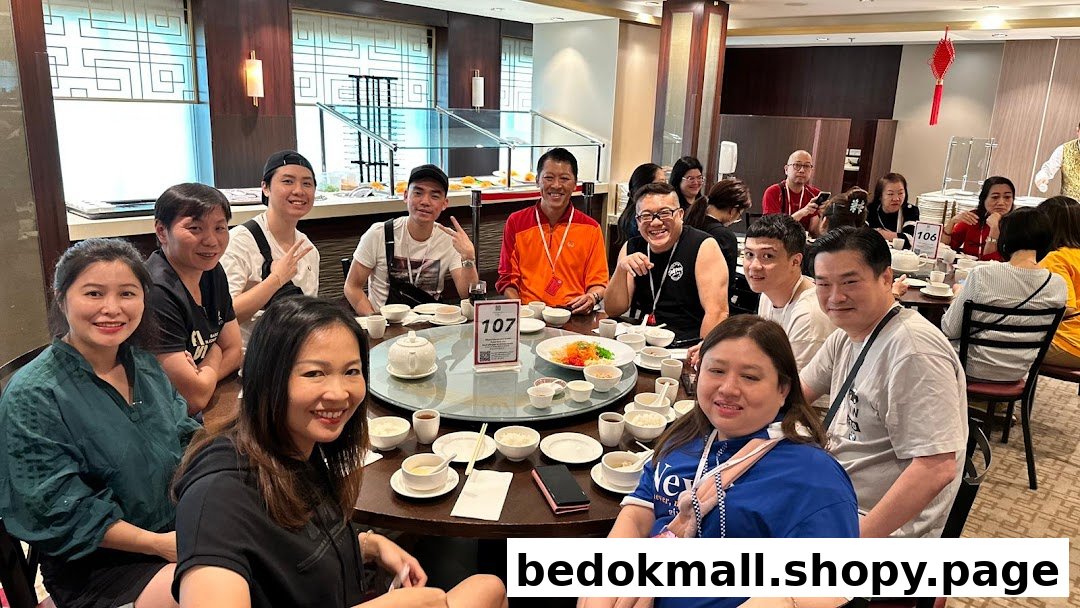 Group of people smiling and dining at a large round table in a restaurant.