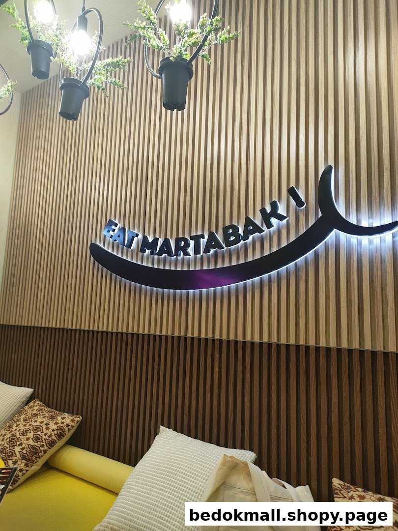 Cafe interior featuring a wooden wall, 'EAT MARTABAK' sign, and yellow seating.
