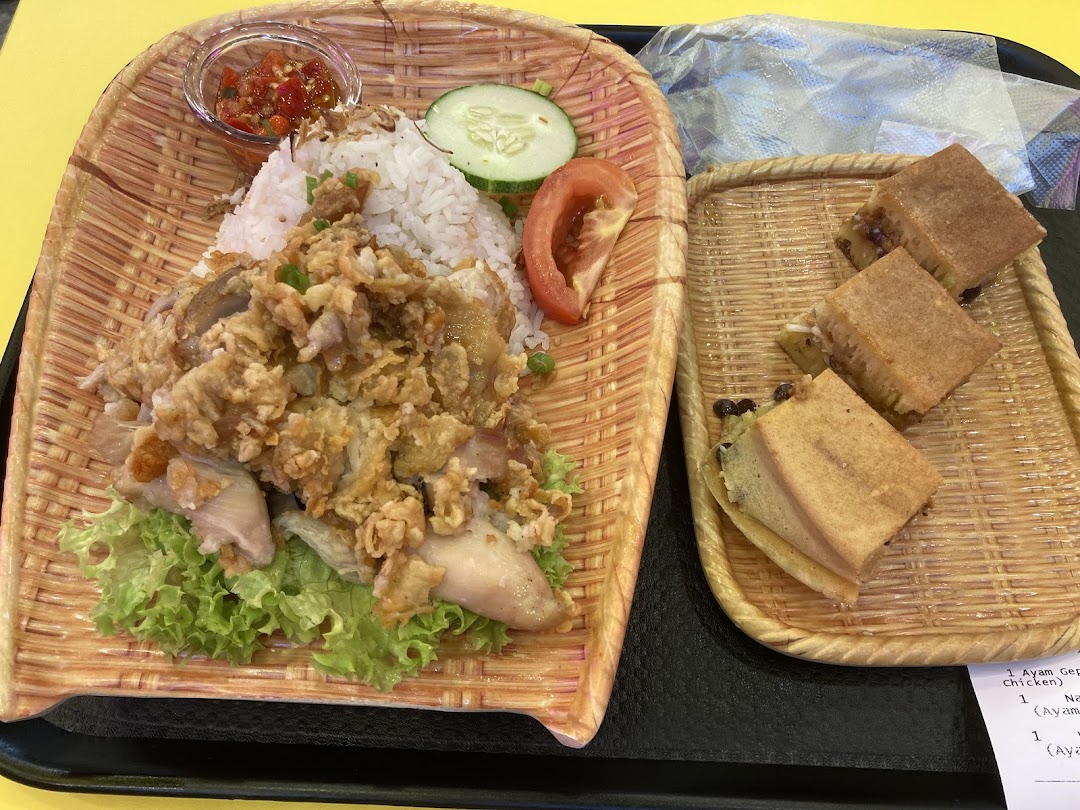 Rice with fried chicken and martabak served on woven trays.