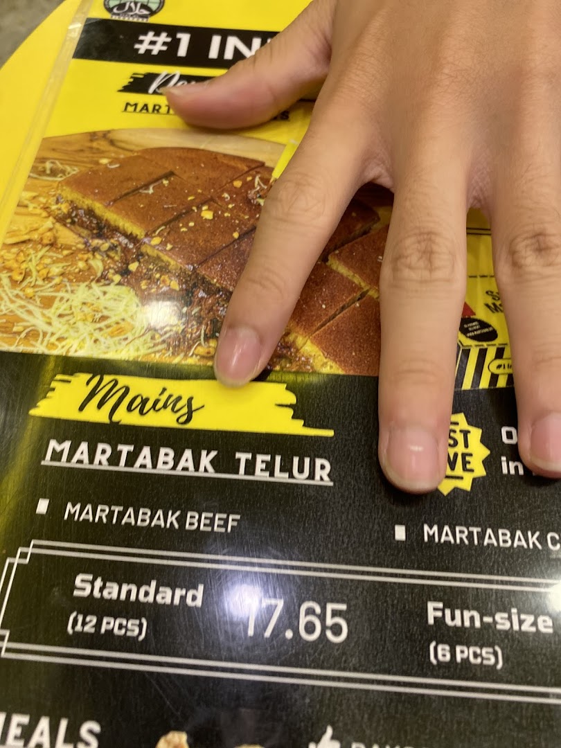 A hand points to a menu displaying Martabak options and prices.
