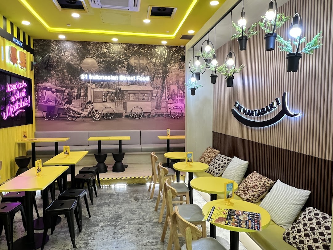 Brightly lit cafe interior with yellow tables, banquette seating, and wall murals.