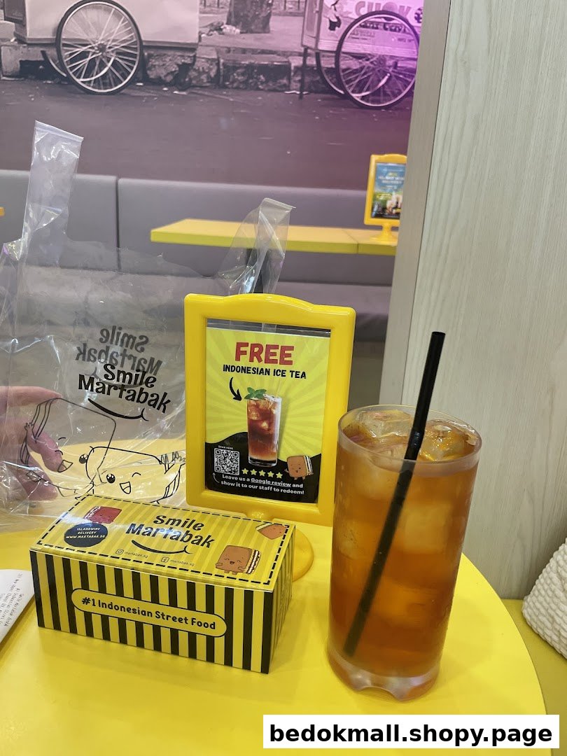 Drink, box, and promotional sign on a yellow table inside a cafe.