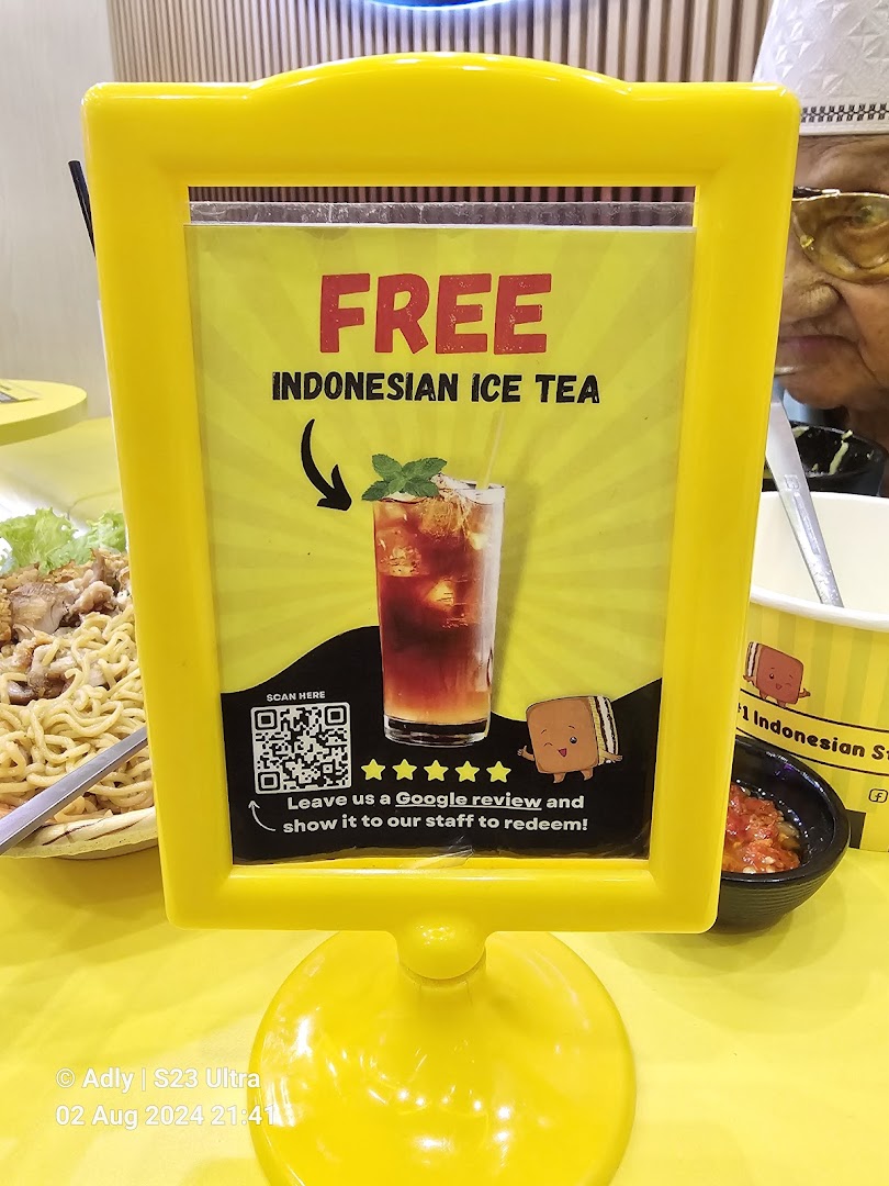A yellow sign promoting free Indonesian ice tea for a Google review.