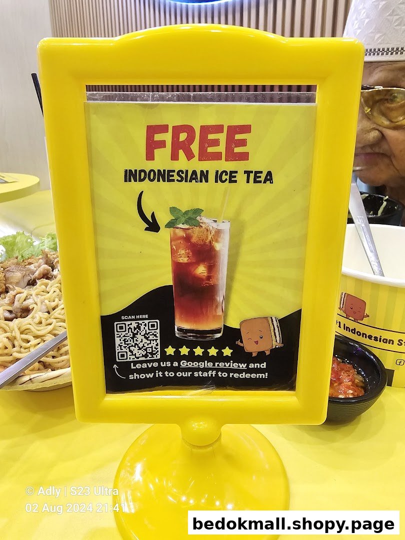 A yellow sign promoting free Indonesian ice tea for a Google review.