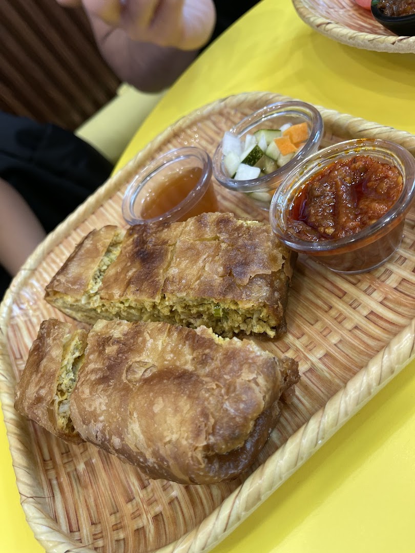 Martabak on a woven tray with three small bowls of sauces.