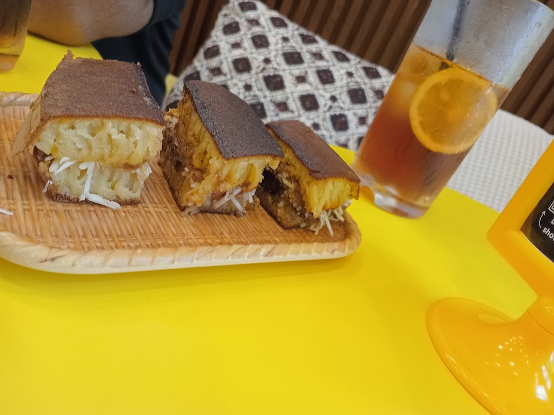 Martabak slices and iced tea on a yellow table.