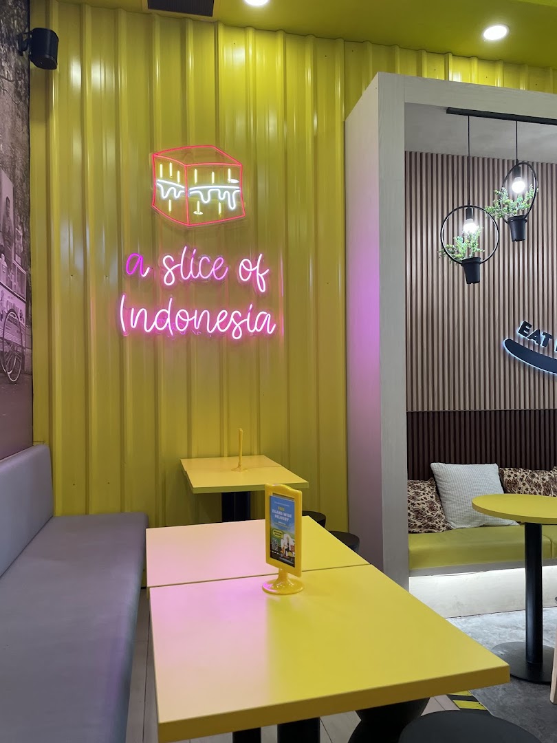 Interior of a cafe with yellow walls, neon sign, tables, and benches.