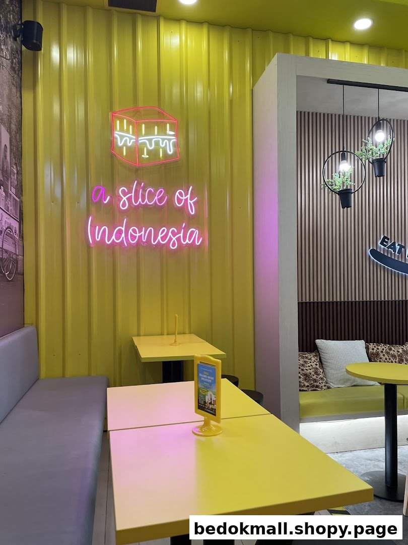 Interior of a cafe with yellow walls, neon sign, tables, and benches.