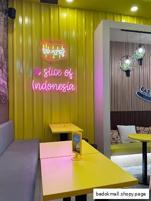 Cafe interior with yellow walls, neon sign, and seating area.