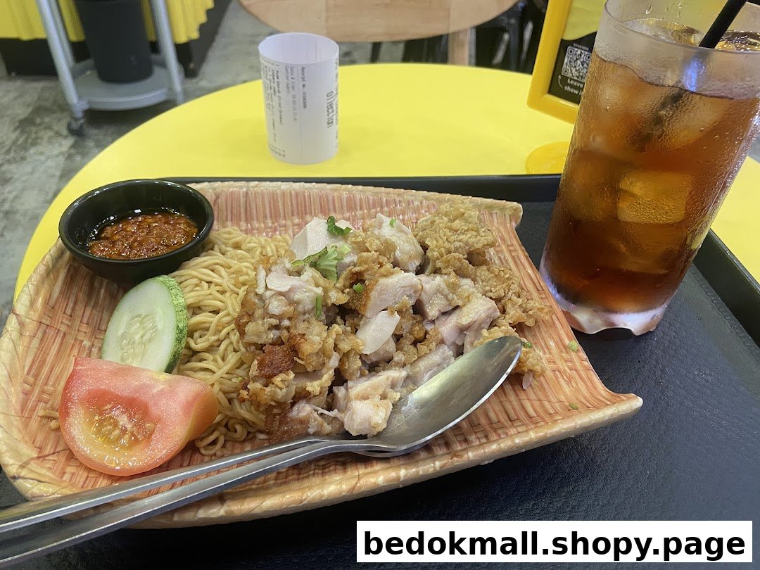 A plate of noodles with chicken and a glass of iced tea on a table.