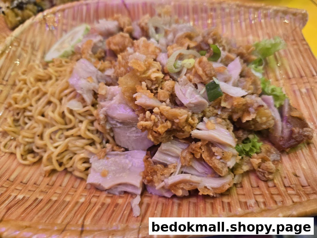 Plate of noodles with fried chicken and greens on a woven tray.