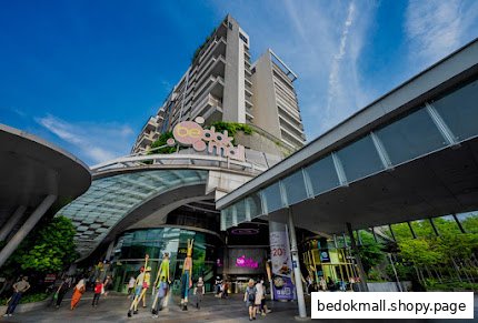 Exterior view of a large modern shopping mall with people.