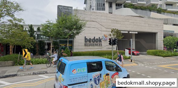Exterior view of a large building with ground-floor commercial spaces and street activity.