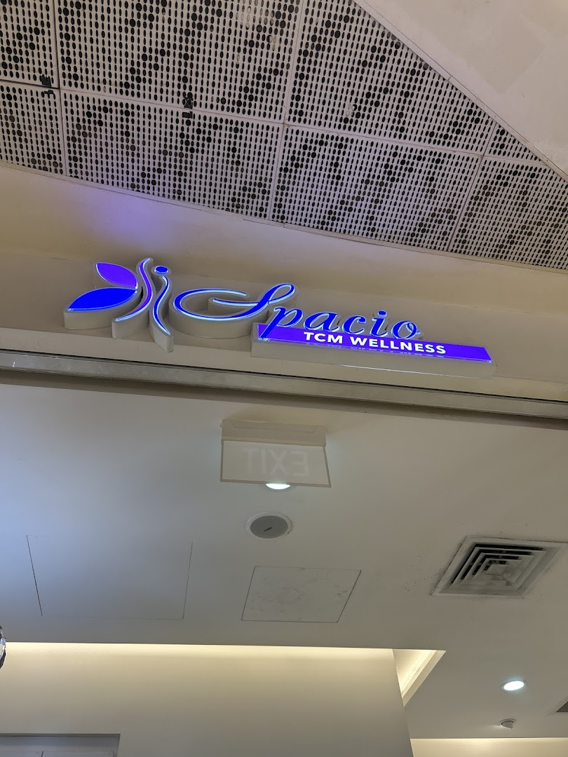 Illuminated 'Spacio TCM Wellness' sign above a shop entrance.